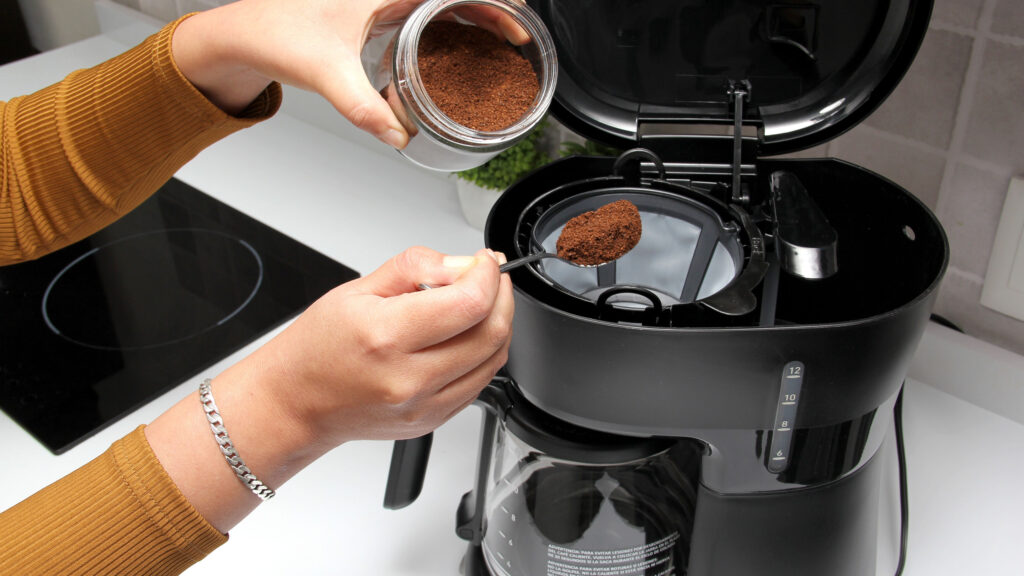 woman putting ground coffee in a coffee filter